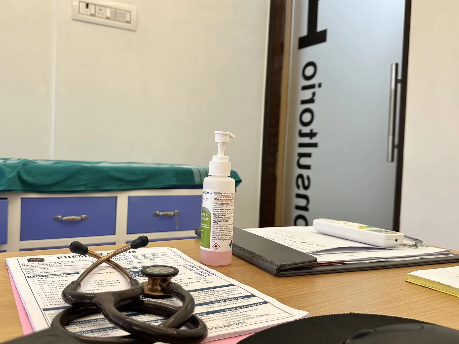 Doctor's desk with a stethoscope in a consultation room, examination couch behind