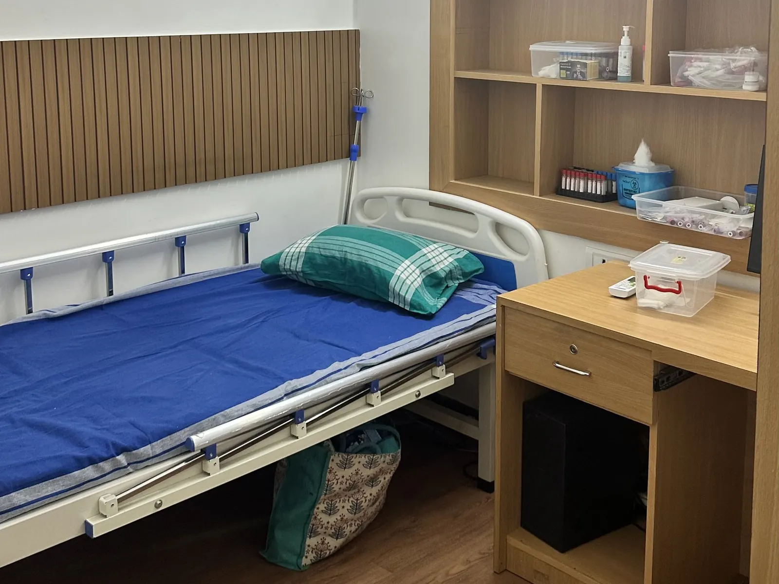 Blood sample collection room with a patient bed and shelves of collection tubes