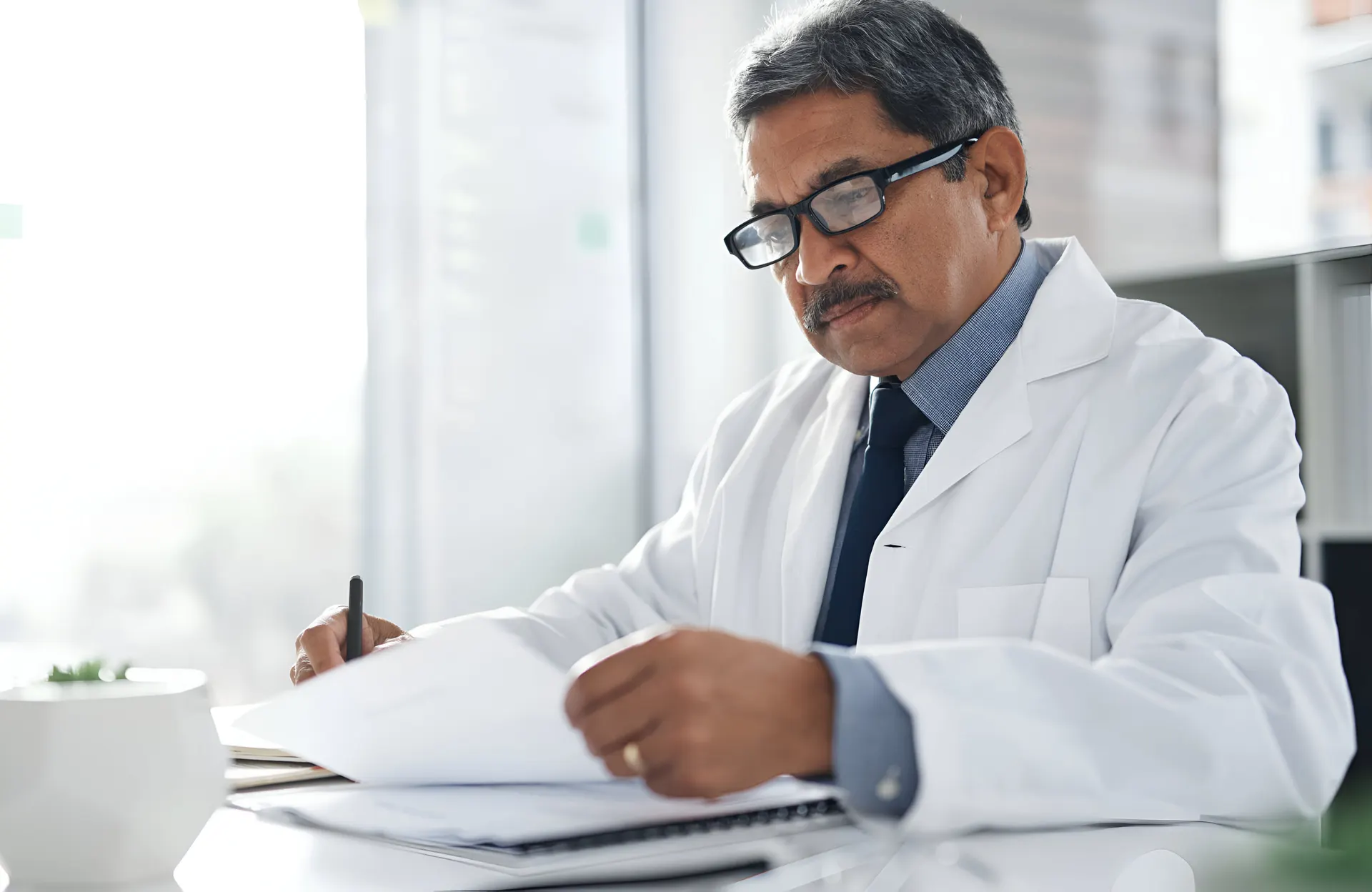 Doctor reviewing medical paperwork — every PingMeDoc certificate verified by a registered practitioner